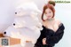 A woman in a black dress holding a stuffed polar bear.