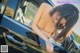 A naked asian woman leaning out the window of a car.