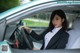 A woman in a business suit sitting in a car.