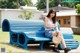 A woman sitting on a blue bench in a park.