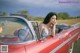 A woman sitting in the driver's seat of a red convertible car.