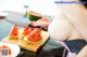 A woman cutting up a slice of watermelon on a cutting board.