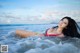 A woman in a bikini laying in the ocean.